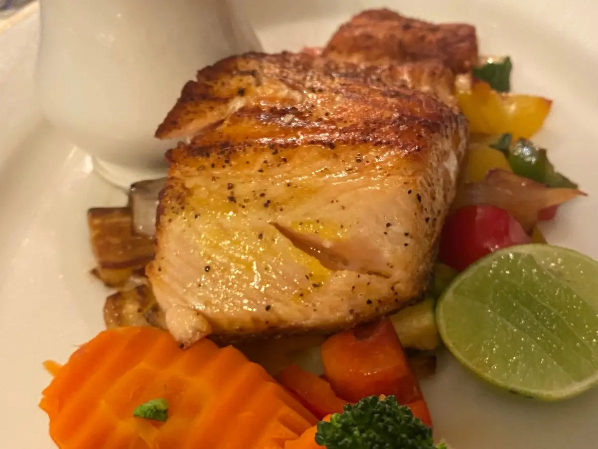 Filete de salmón con brócoli, zanahoria y lima en un plato blanco