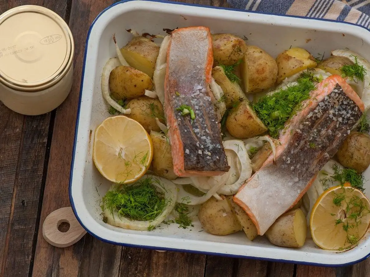 Bandeja con lomos de salmón con piel, patatas pequeñas, rodajas de limón y hinojo