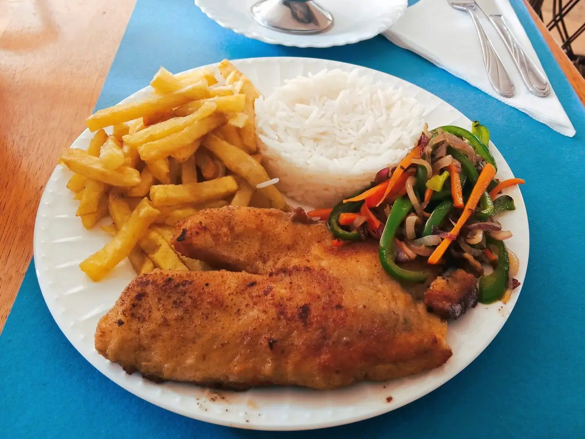 Filetes de pescado dorados con patatas, arroz y verduras salteadas