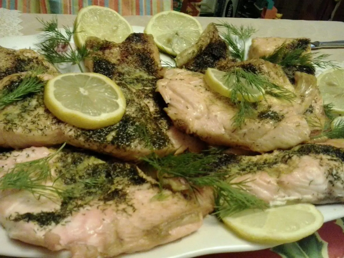 Filetes de salmón al horno con eneldo fresco y rodajas de limón en una fuente