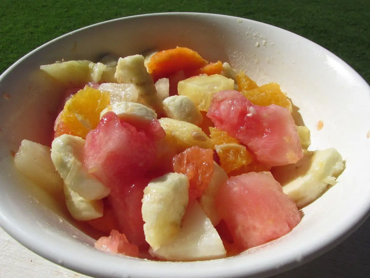 Cuenco blanco con macedonia de sandía, papaya, piña, naranja y plátano troceados
