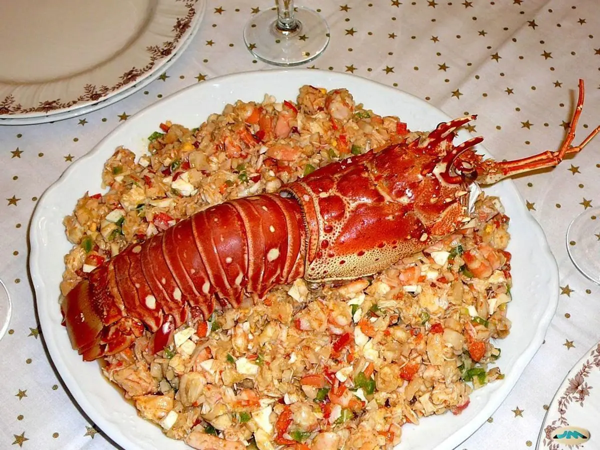 Salpicón gallego de marisco picado con una langosta roja encima en un plato blanco
