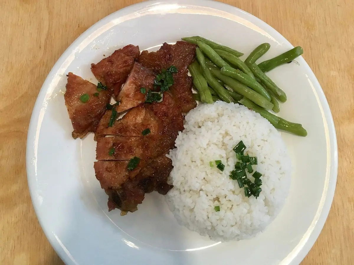 Plato blanco con trozos de cerdo salteados, arroz blanco y judías verdes