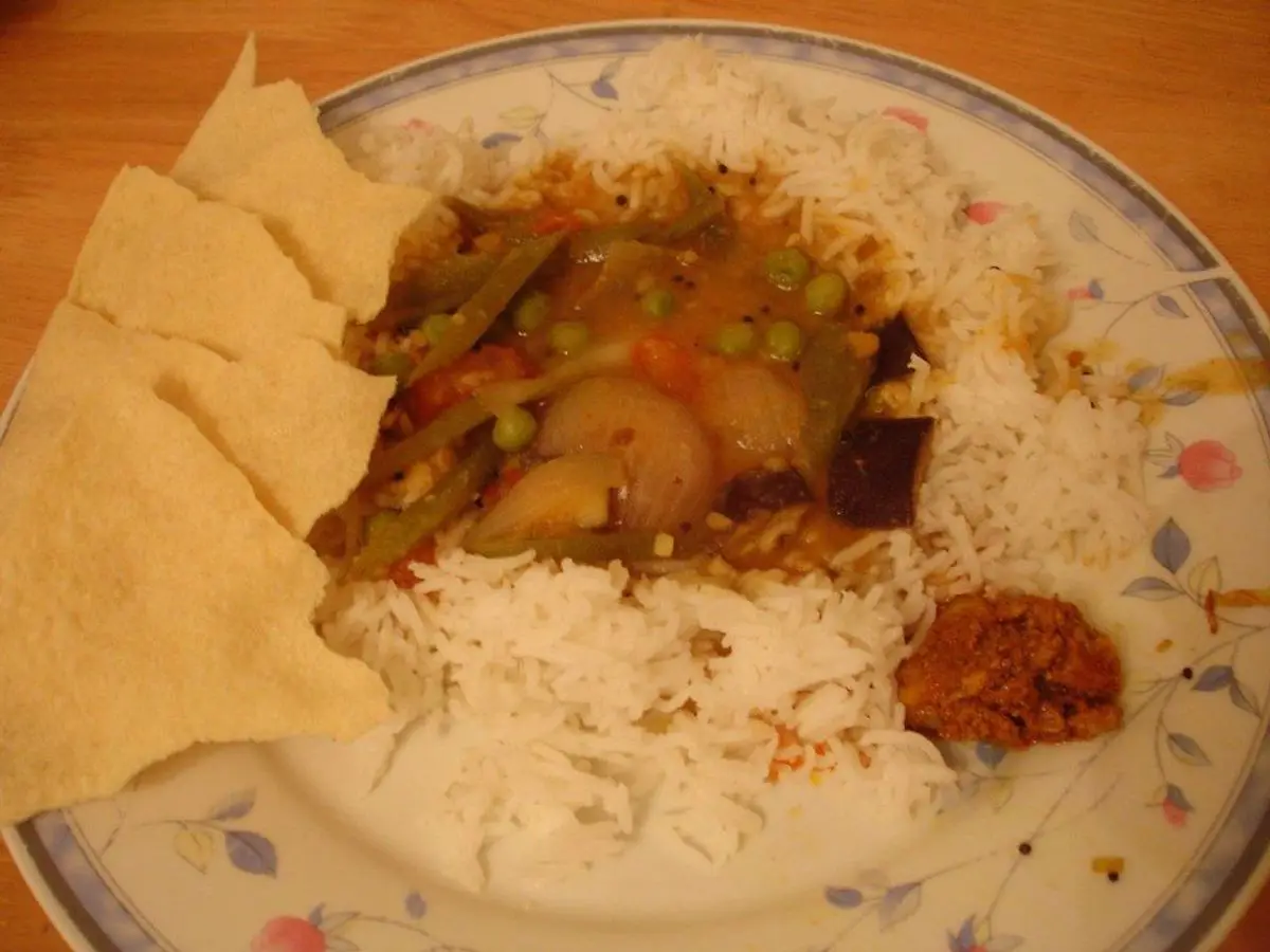Plato con arroz blanco, guiso de verduras con guisantes y zanahoria y crujientes papadum