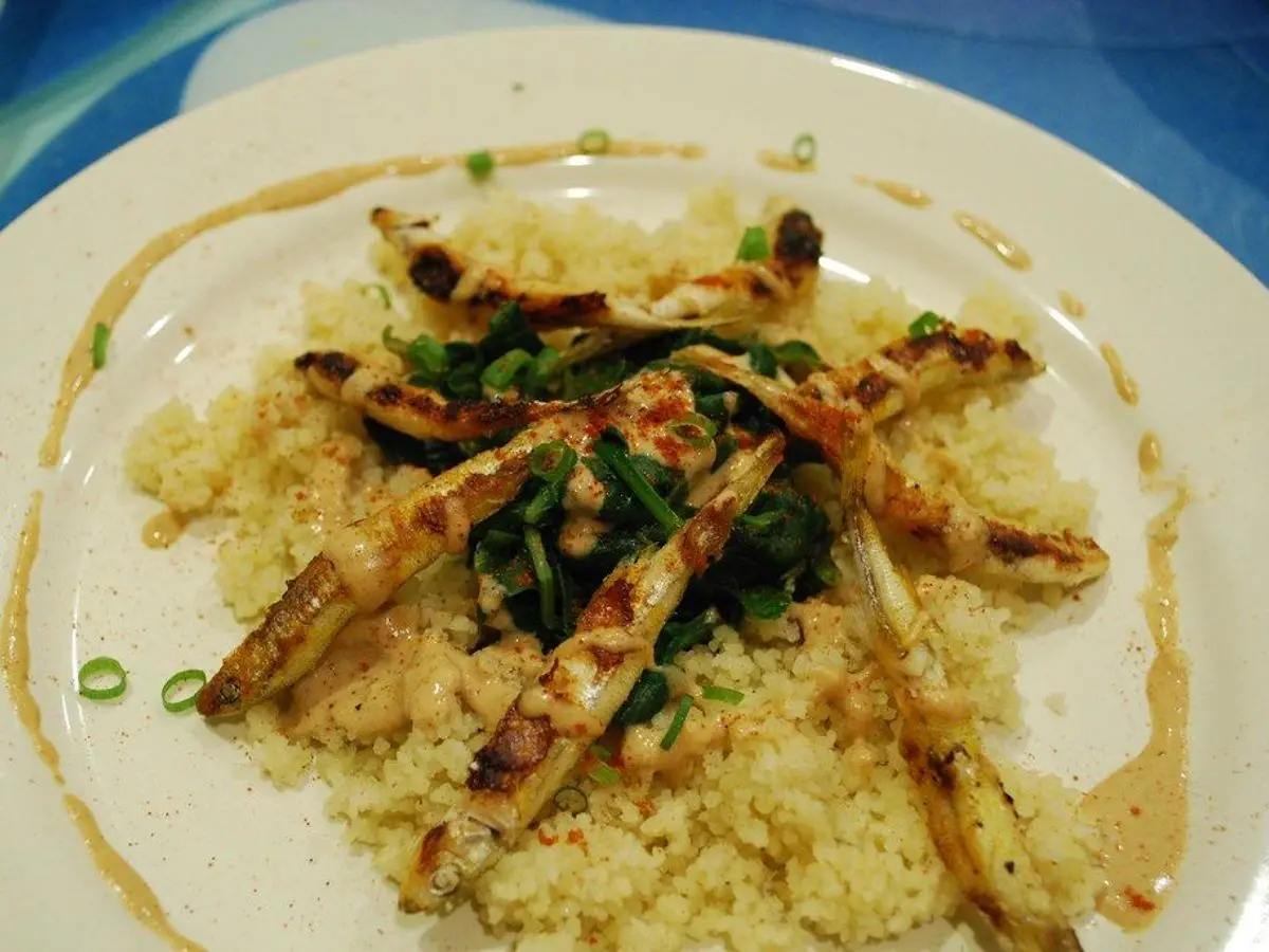 Plato con pescado a la plancha sobre cuscús con salsa de tahini y cebolleta picada