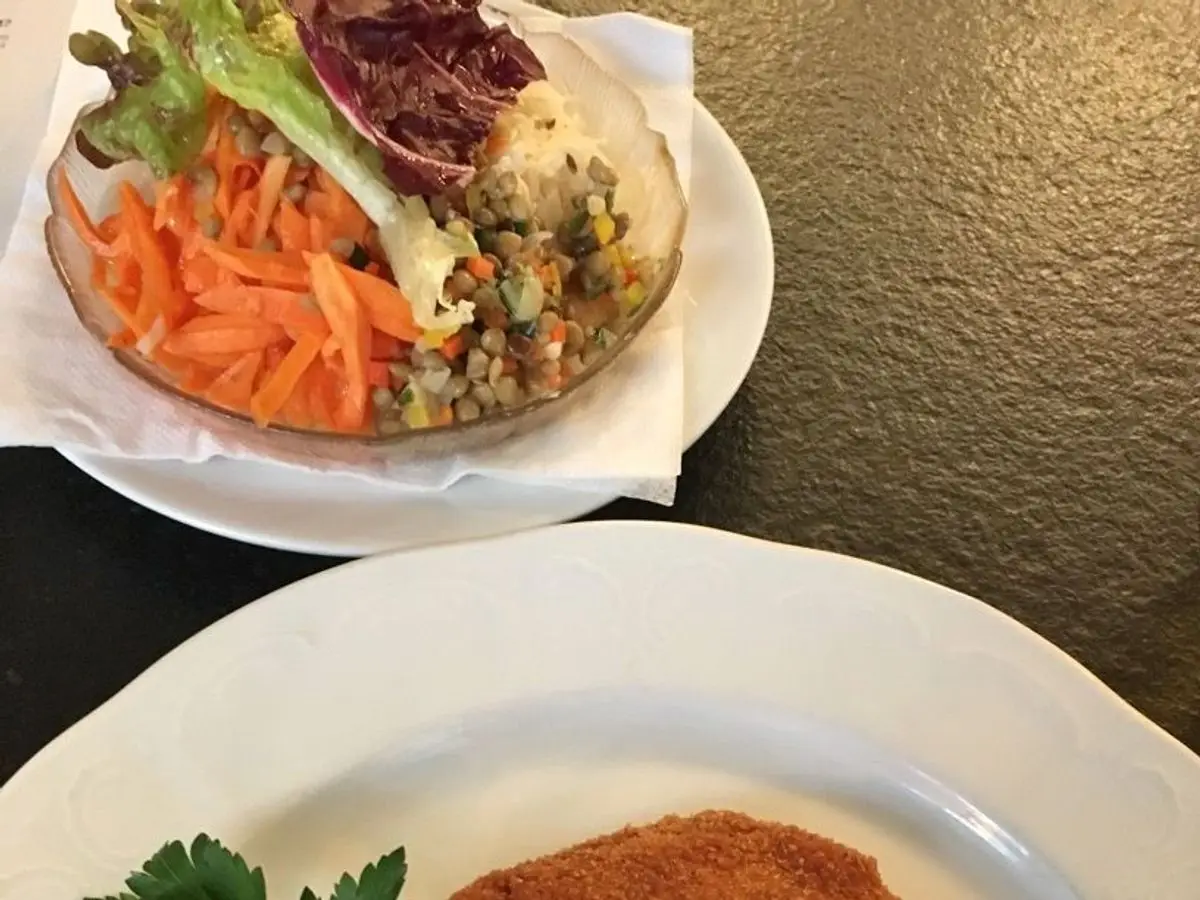 Filete empanado dorado con perejil y una cuña de limón en un plato blanco