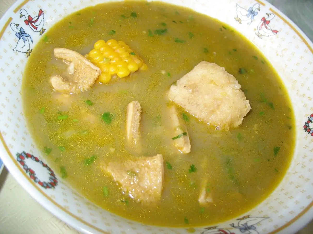 Plato hondo de sancocho con caldo verde, mazorca de maíz y trozos de yuca y plátano