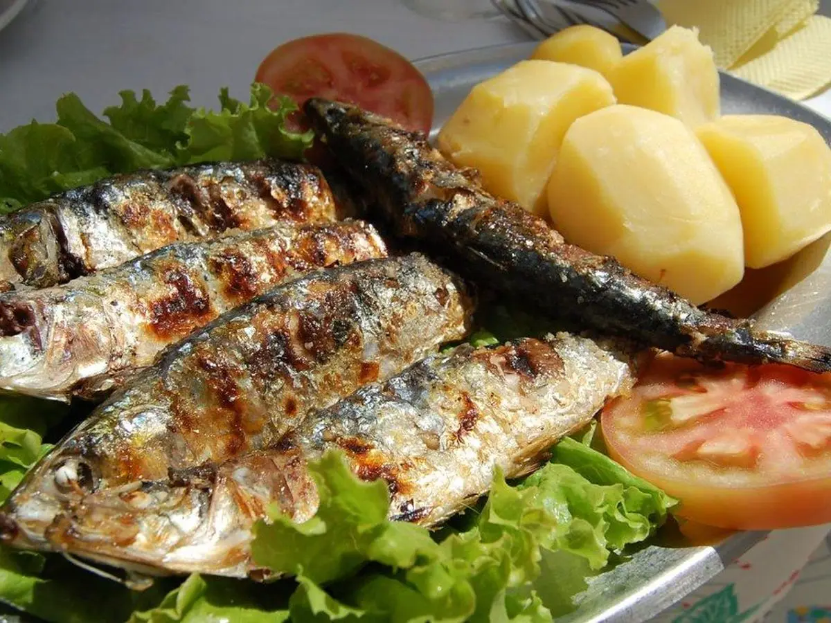 Sardinas asadas con patatas cocidas, lechuga y tomate en una fuente