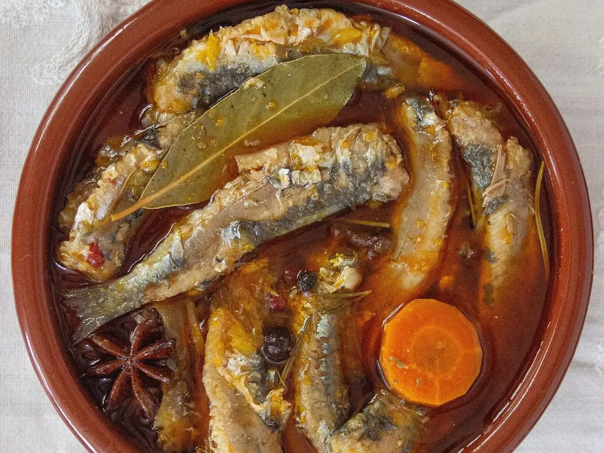Cazuela de barro con sardinas en escabeche, hoja de laurel y rodajas de zanahoria