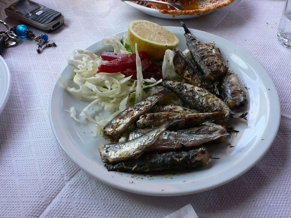 Sardinas a la parrilla con ensalada de cebolla y limón en un plato blanco