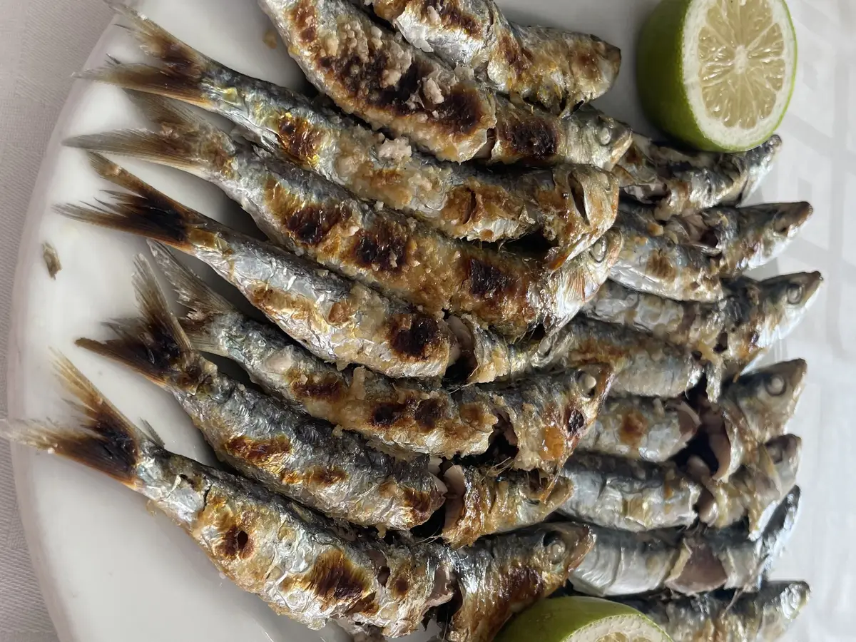 Sardinas asadas en fila con lima en un plato blanco