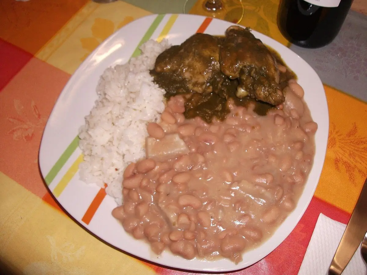 Guiso de carne en salsa verde de cilantro con arroz blanco y frijoles en un plato decorado