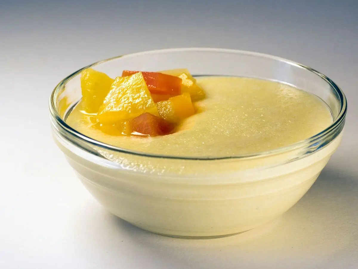 Cuenco de cristal con sémola cremosa con leche y gajos de naranja
