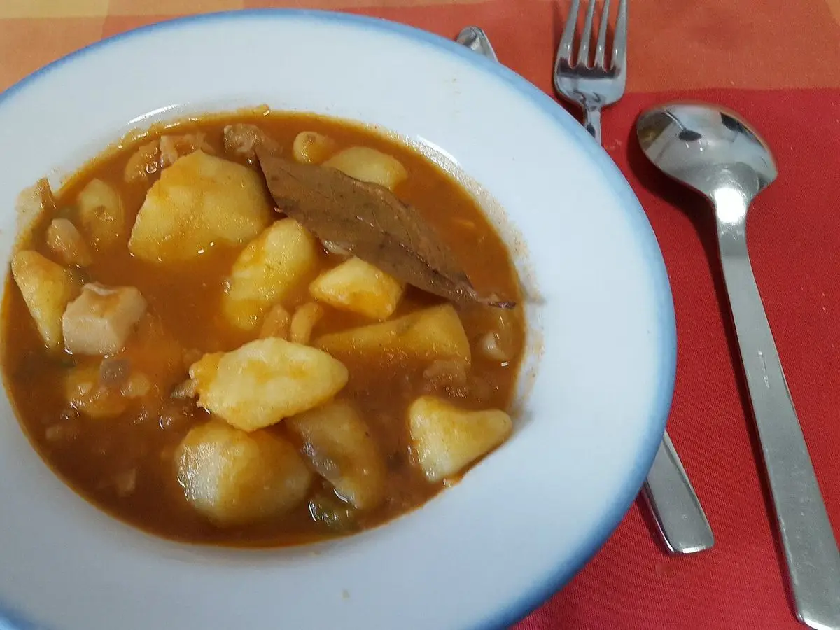 Plato hondo de sepia guisada con patatas en salsa de tomate y una hoja de laurel