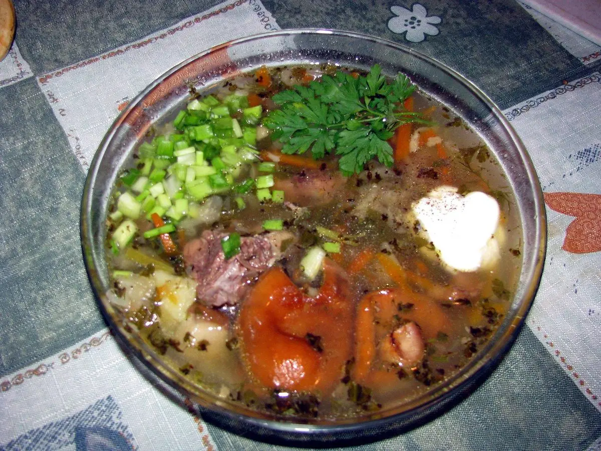 Cuenco de cristal con sopa de col y carne, cebolleta, eneldo y una cucharada de nata agria