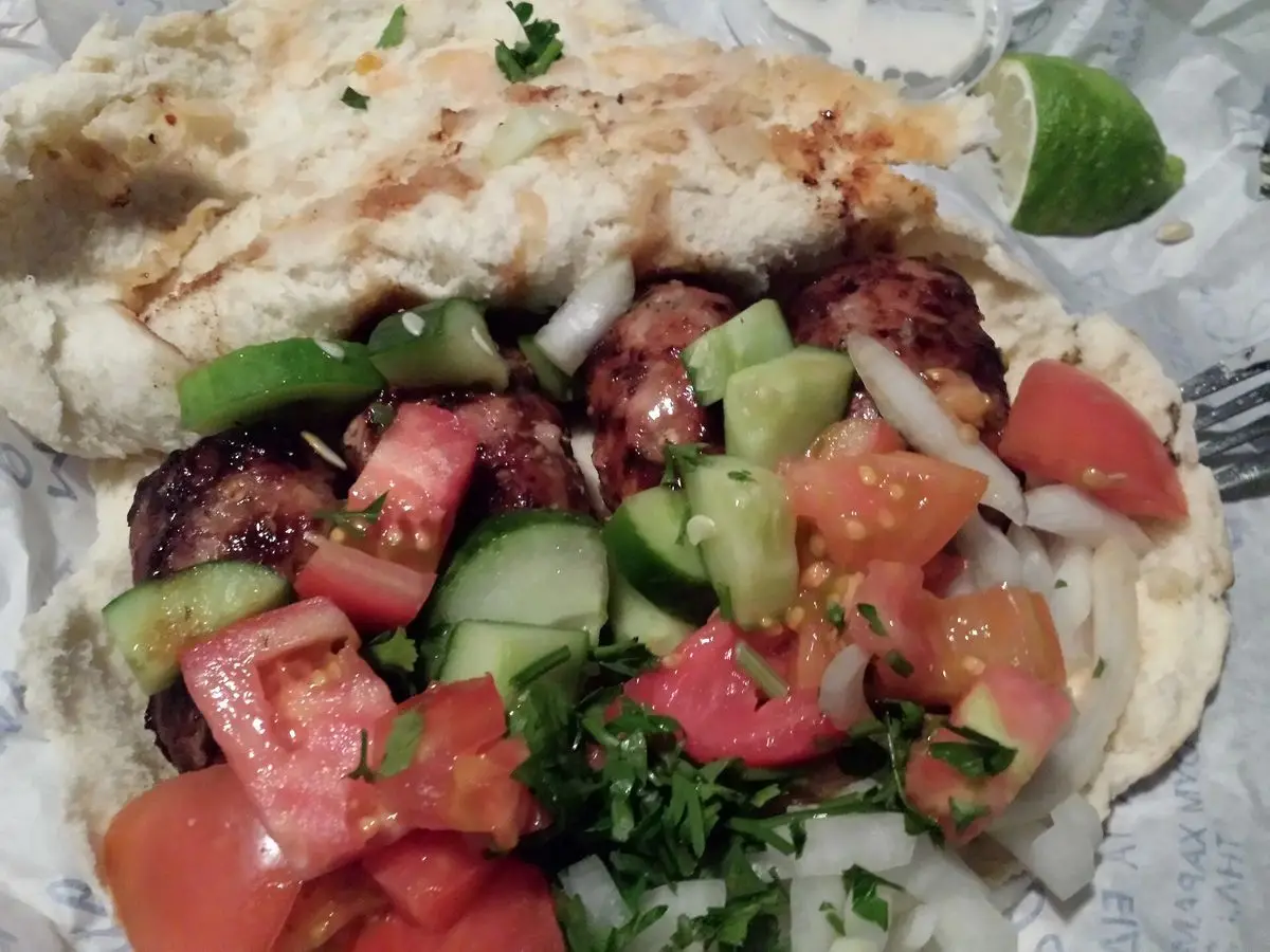 Sheftalia en pan de pita con tomate, pepino, cebolla y lima