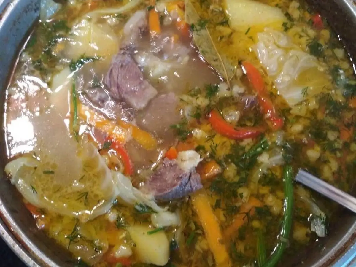 Olla de sopa espesa con trozos de carne, patata, zanahoria y pimiento rojo