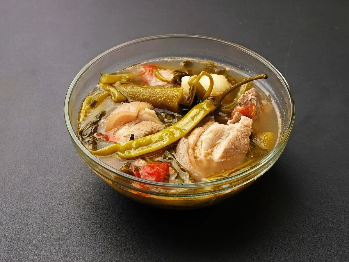 Cuenco de sinigang filipino con costillas de cerdo, guindilla verde, tomate y verduras en caldo