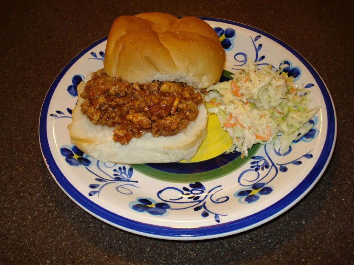 Bocadillo sloppy joe de carne picada en pan blando con ensalada de col en un plato