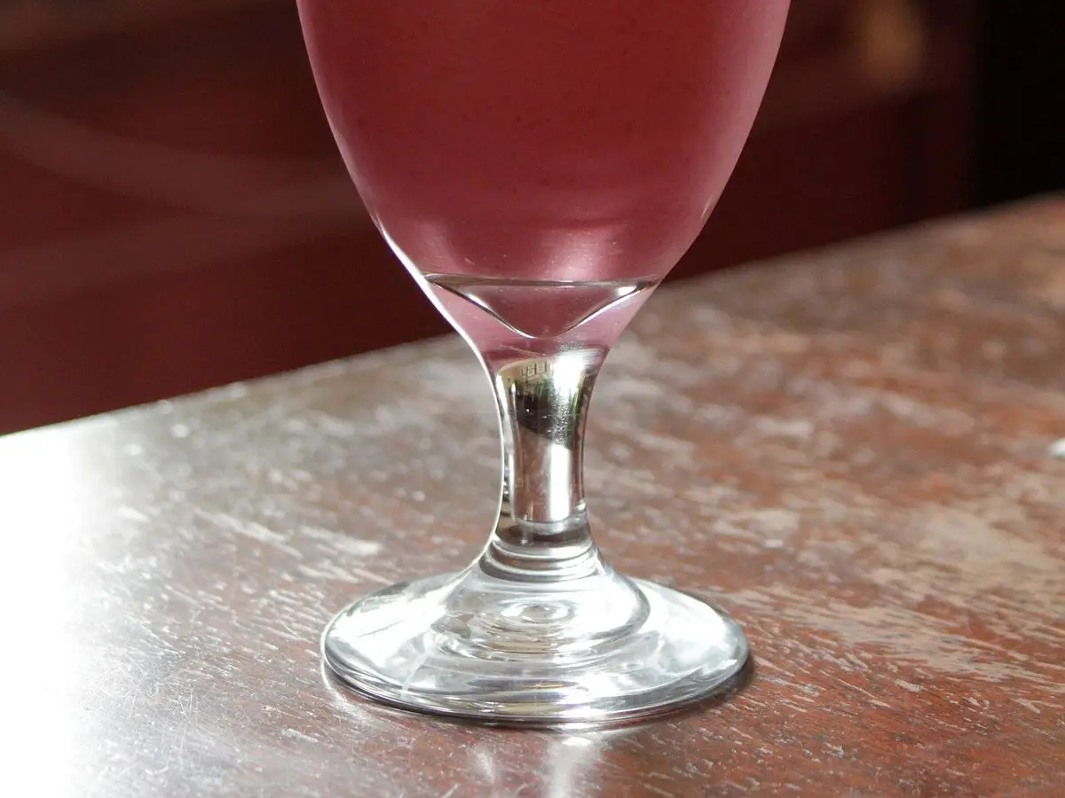 Copa alta con un batido de frutos rojos de color rosado intenso