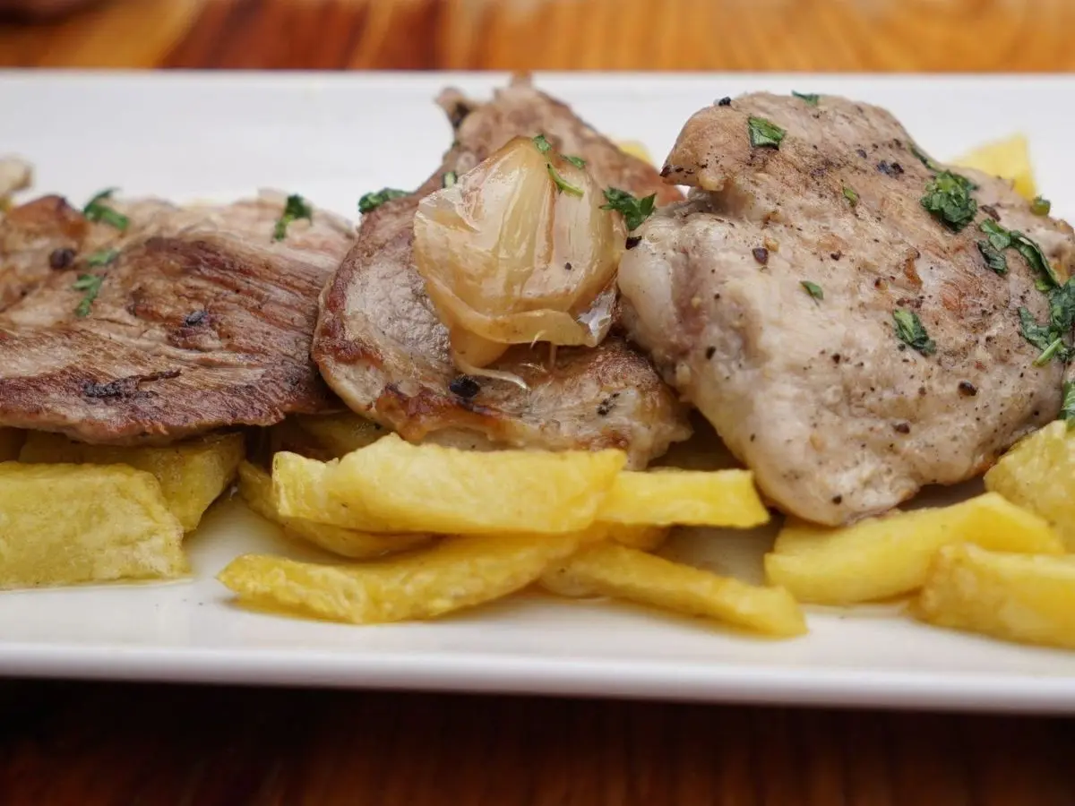 Medallones de solomillo de cerdo a la plancha con un diente de ajo asado y patatas fritas