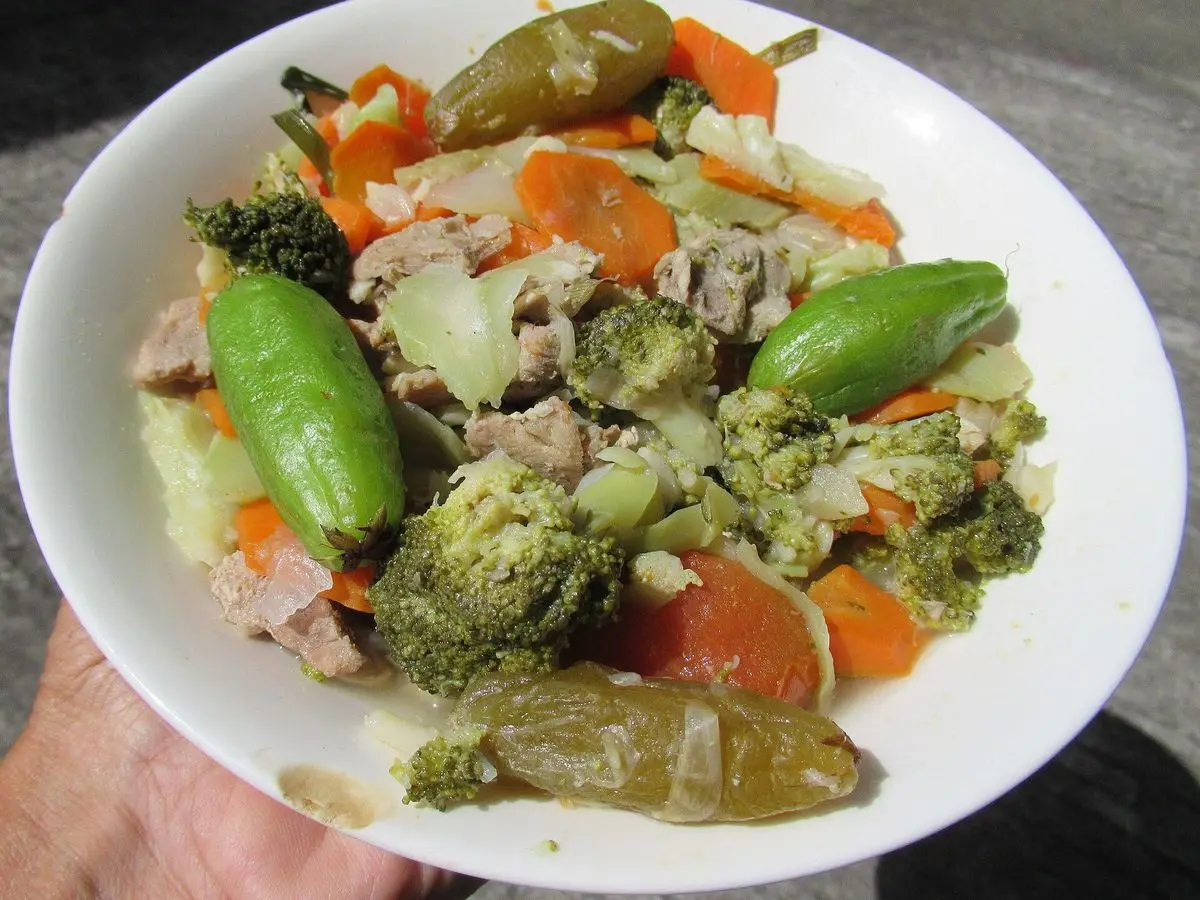 Plato blanco con trozos de cerdo, brócoli, zanahoria y pimientos verdes cocidos
