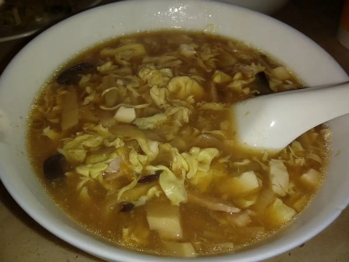 Plato hondo de sopa agripicante con tofu en dados, hilos de huevo y setas