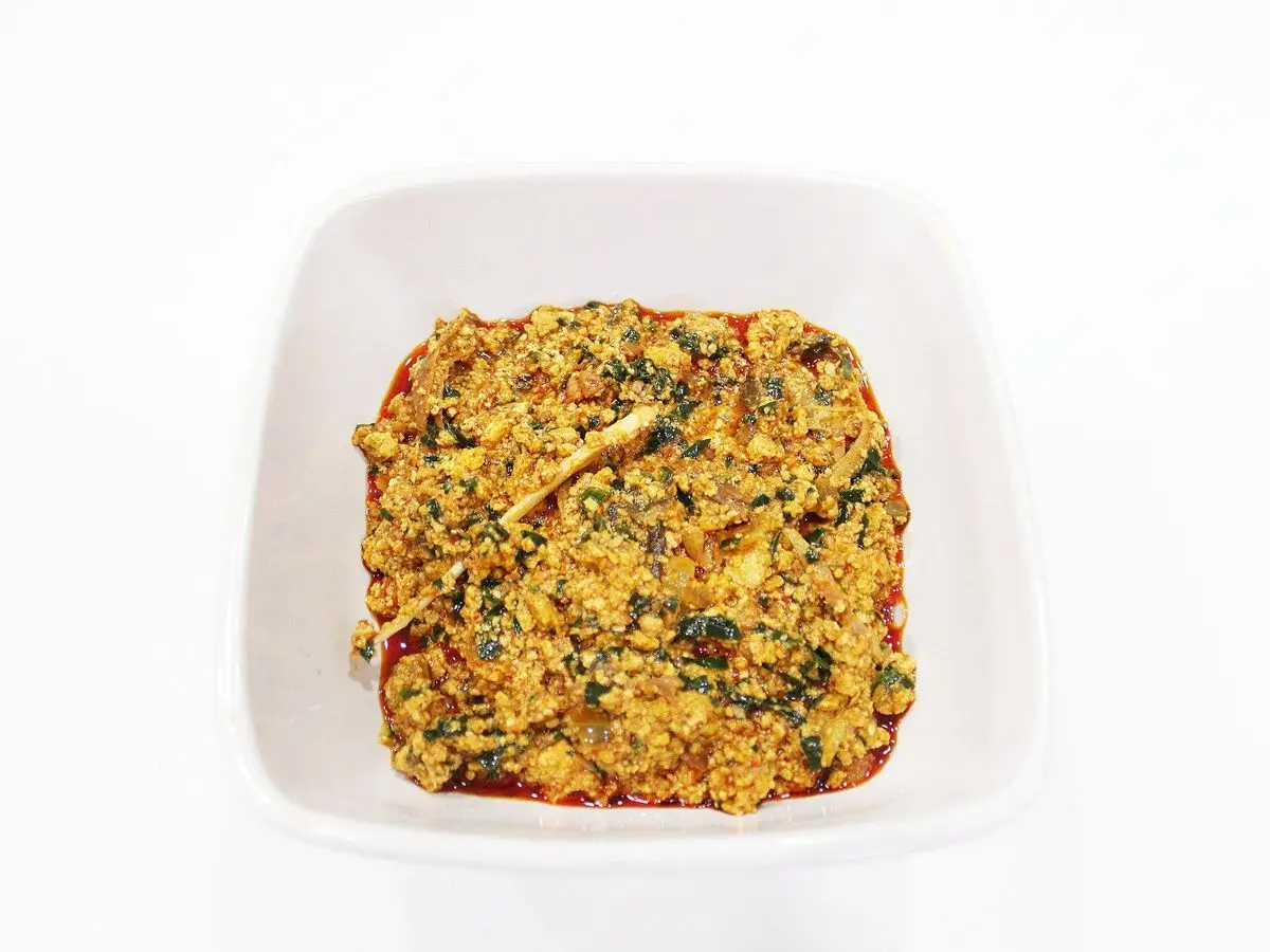 Cuenco cuadrado blanco con sopa espesa de egusi con hojas verdes