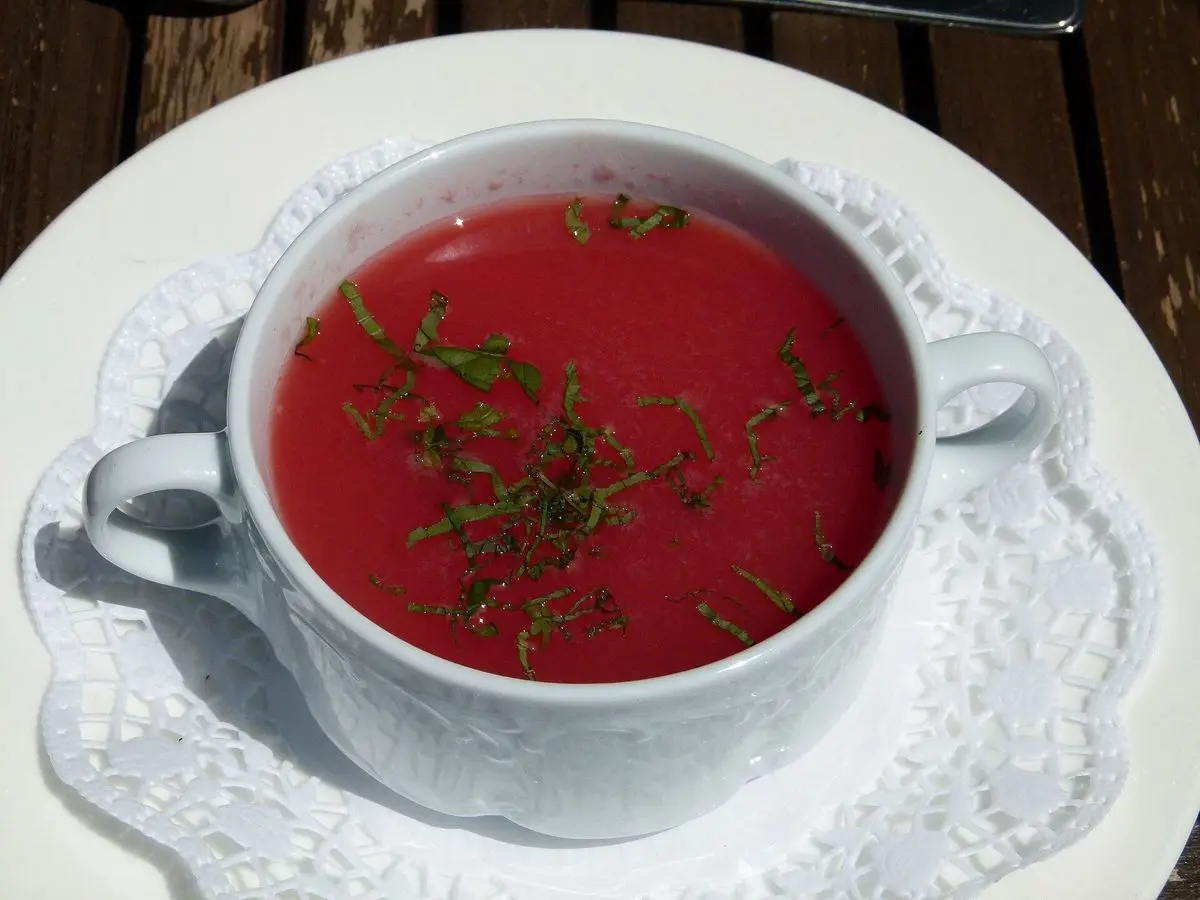 Taza de sopa fría de sandía de color rojo con hierbas picadas por encima