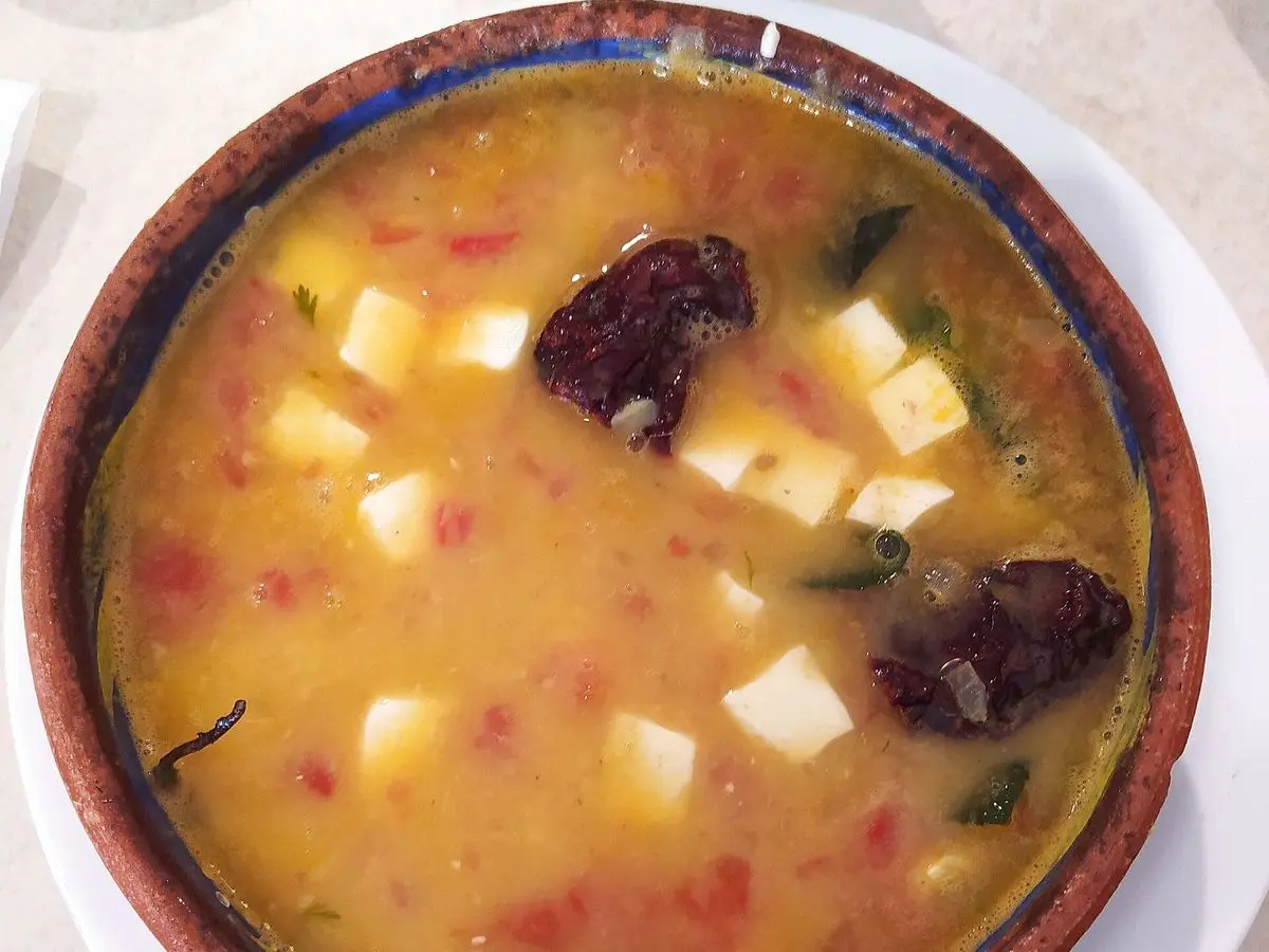 Cazuela de barro con sopa de habas, dados de queso fresco y chile seco
