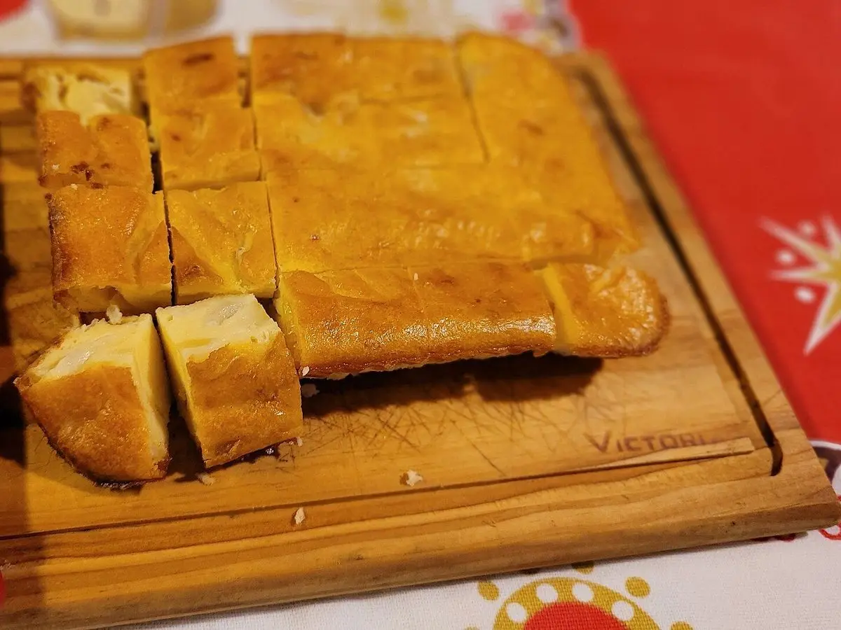Sopa paraguaya, pastel de maíz y queso cortado en porciones sobre una tabla de madera