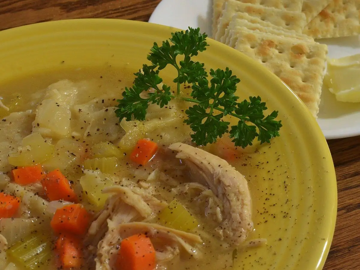 Plato de sopa de pavo con zanahoria, apio y perejil, con galletas saladas al lado