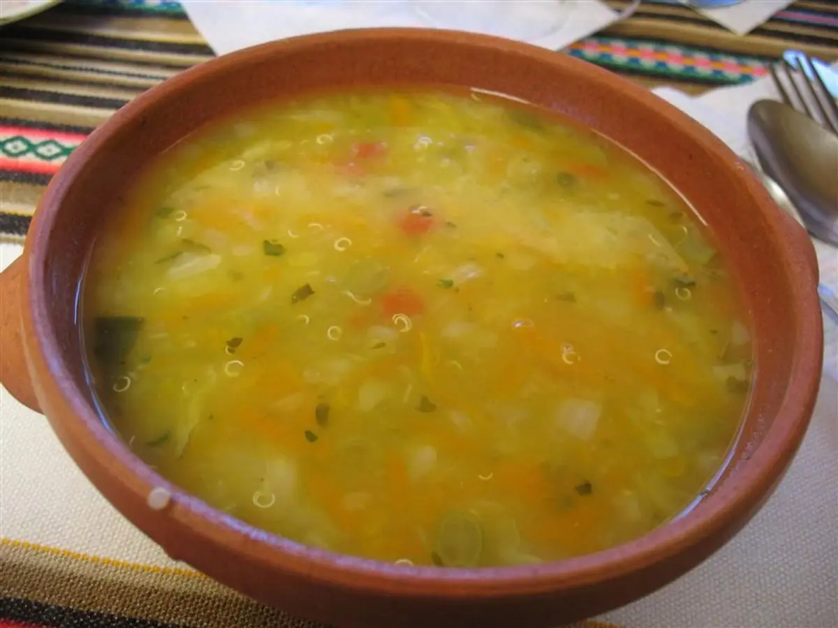 Cuenco de barro con sopa de quinoa amarilla con verduras