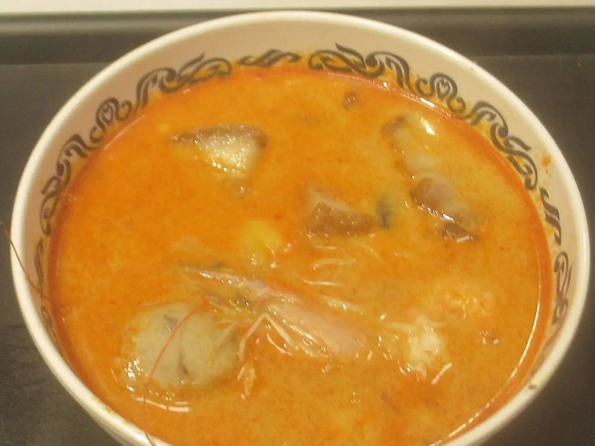 Cuenco de sopa naranja con gamba, setas y hierbas