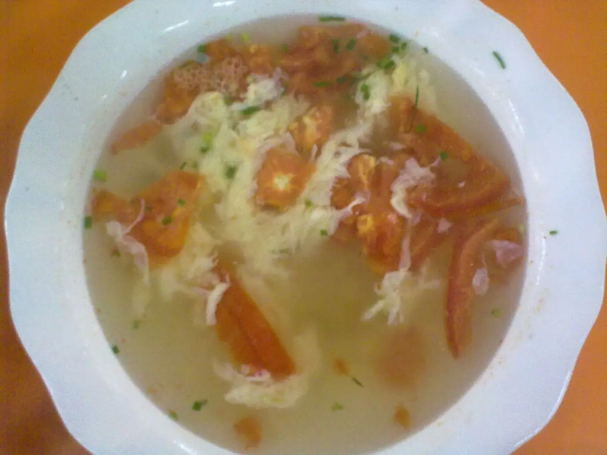 Plato hondo de sopa con tomate, huevo y verdura picada en caldo claro