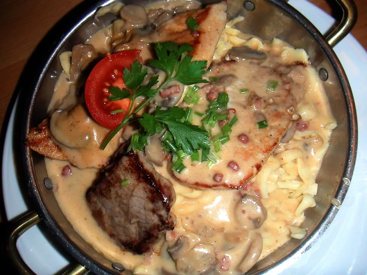 Sartén con spätzle, filete de cerdo, salsa cremosa de champiñones, tomate y perejil