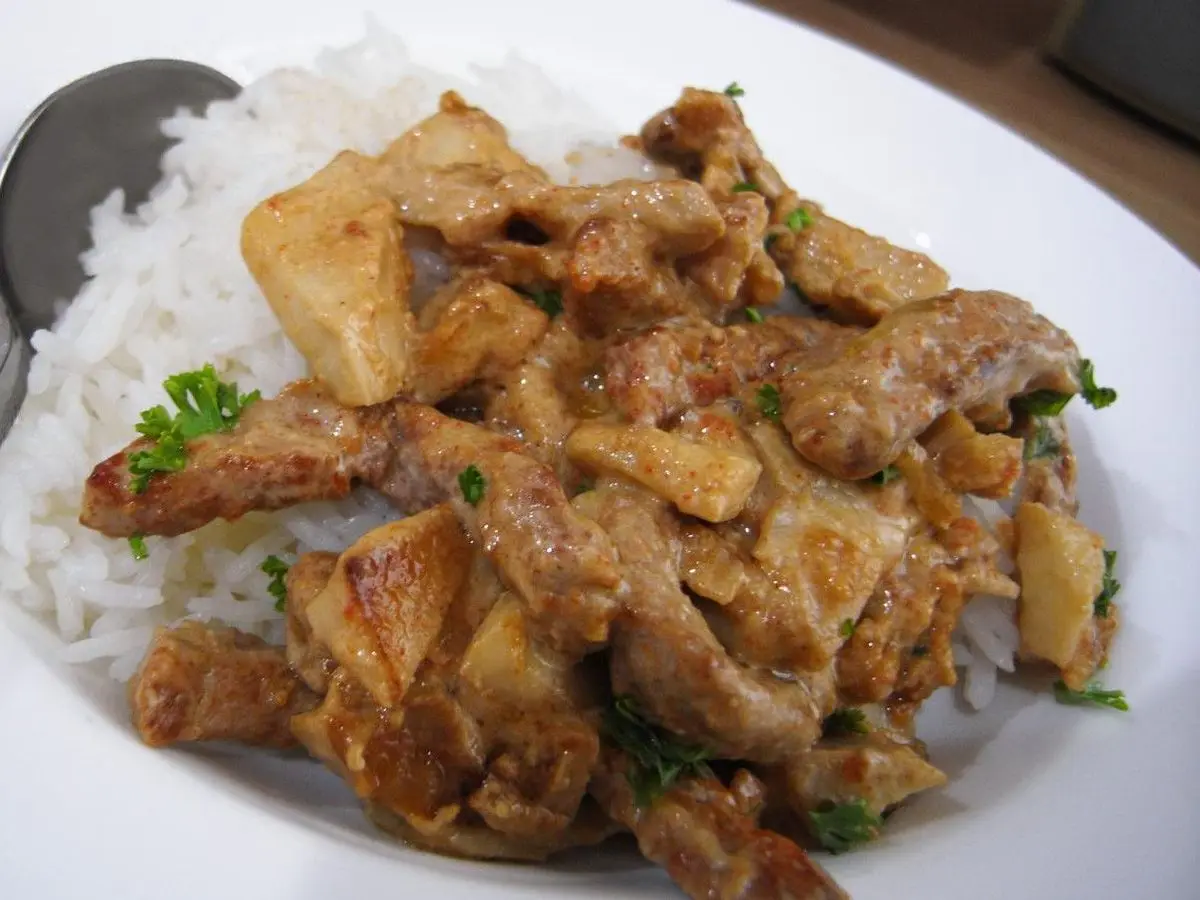 Tiras de ternera en salsa cremosa con perejil sobre arroz blanco en un plato