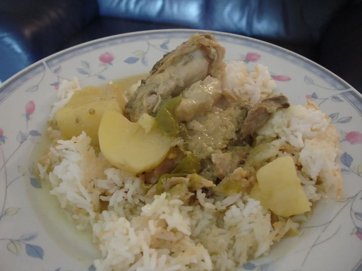 Plato con arroz blanco, pollo guisado y patata en trozos