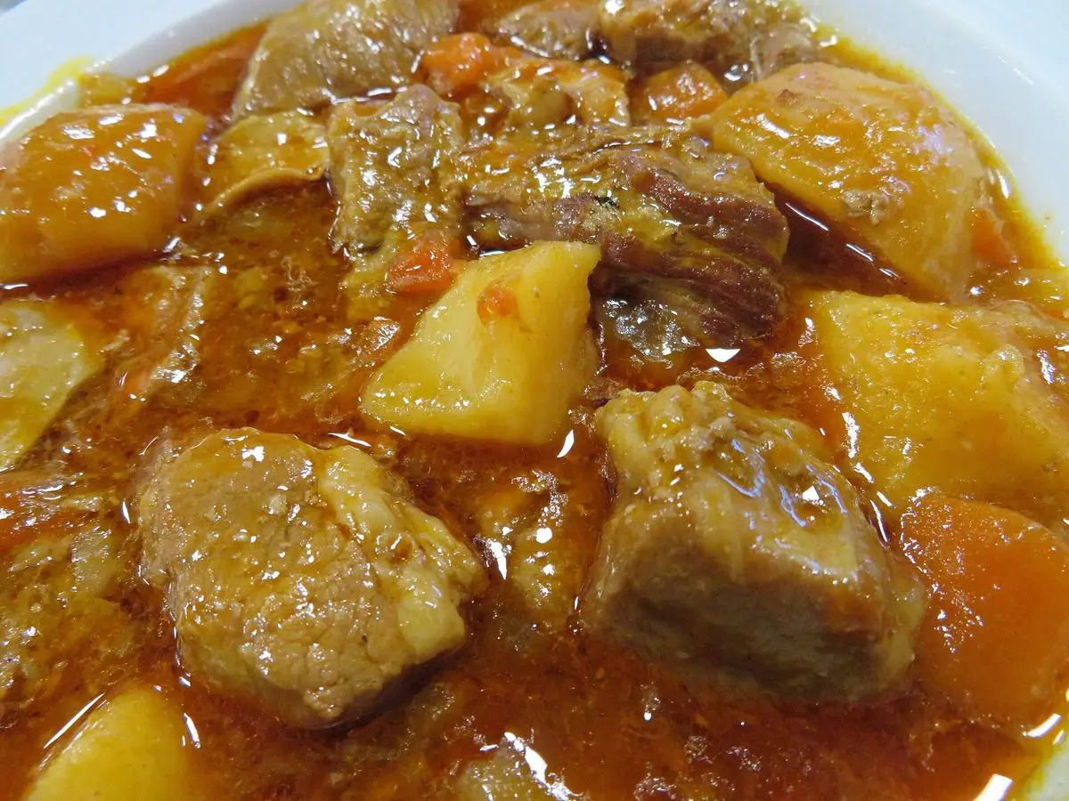 Primer plano de tacos de ternera guisados con patatas en salsa roja de pimiento y tomate