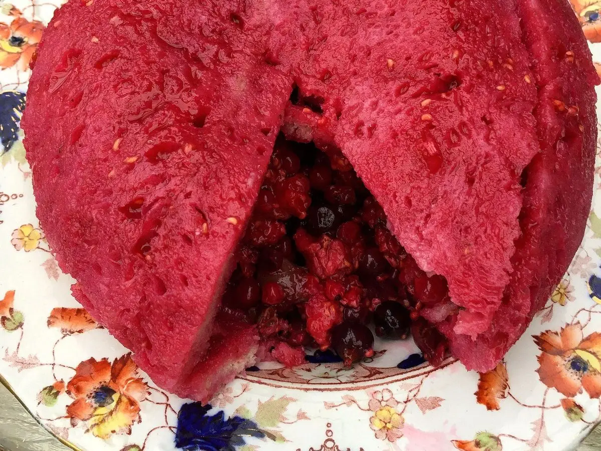 Summer pudding rojo cortado, con pan empapado de jugo y frutos rojos en el interior