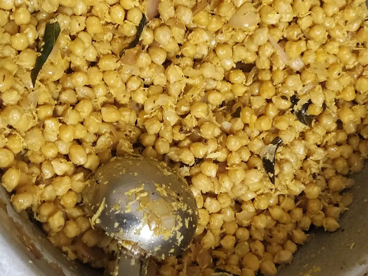 Sundal, garbanzos cocidos con especias y semillas, vistos desde arriba con un cucharón metálico