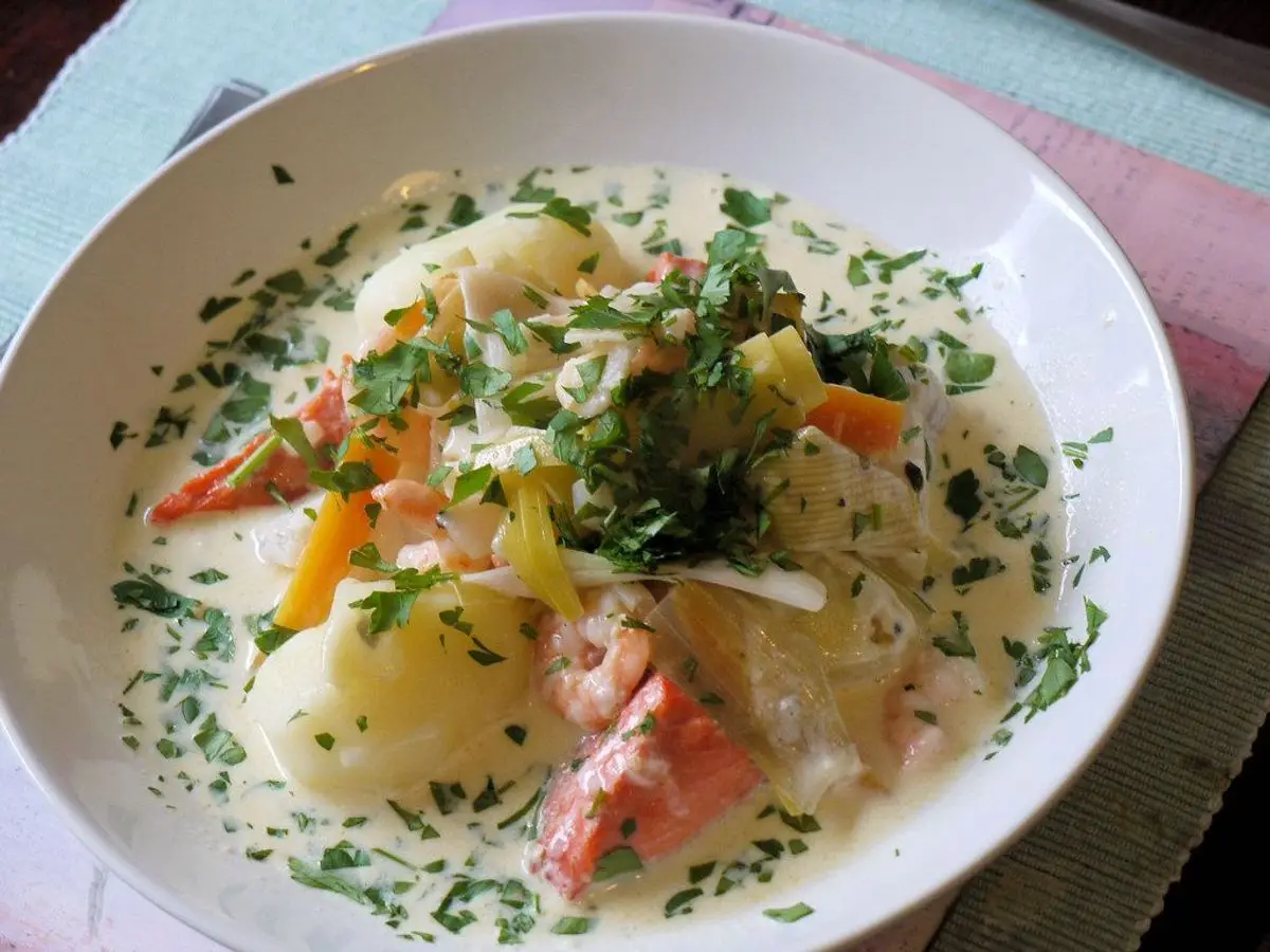Plato hondo de guiso de pescado con patata, zanahoria y perejil