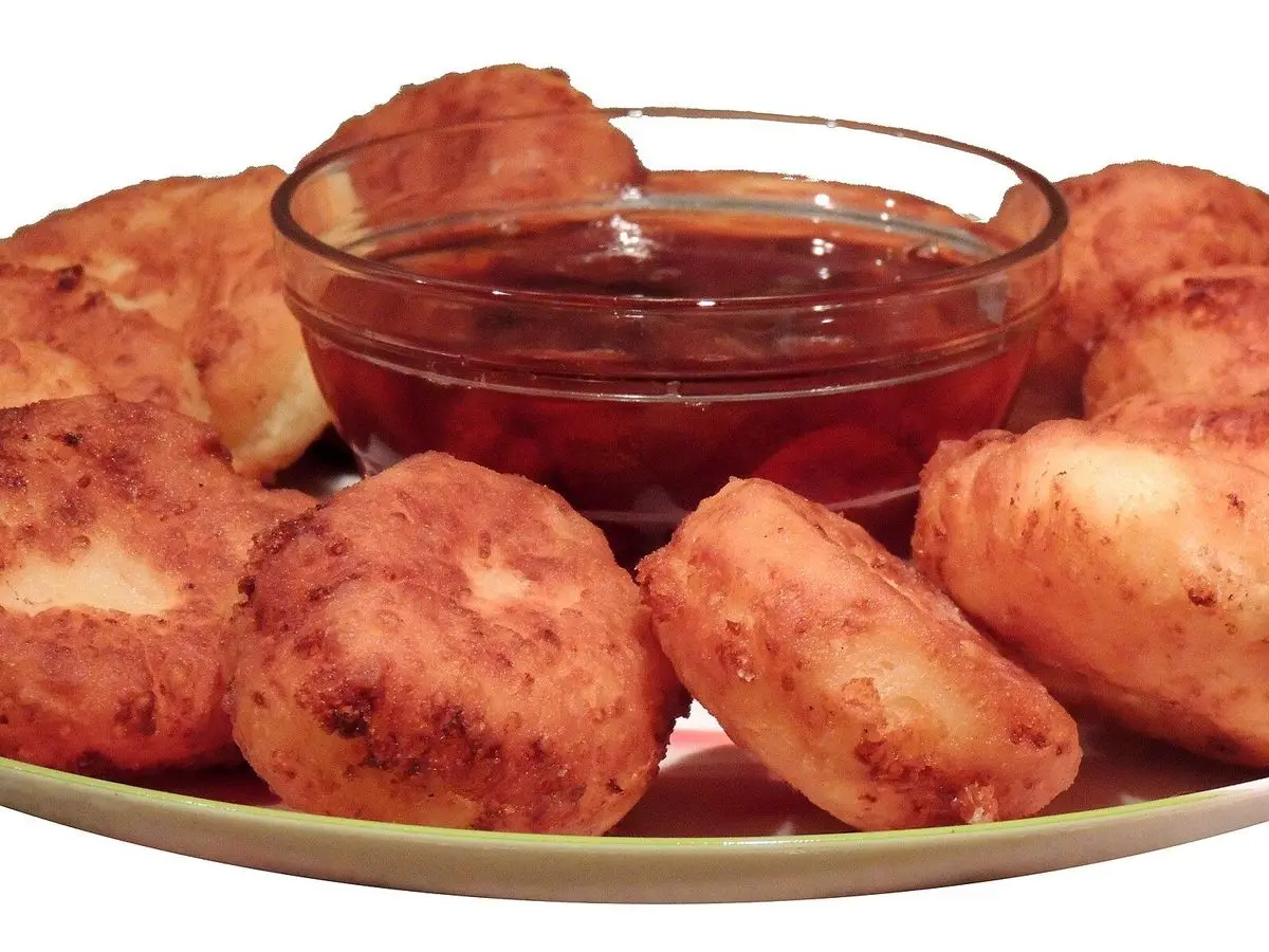 Tortitas fritas de requesón syrniki con mermelada roja en un cuenco de cristal