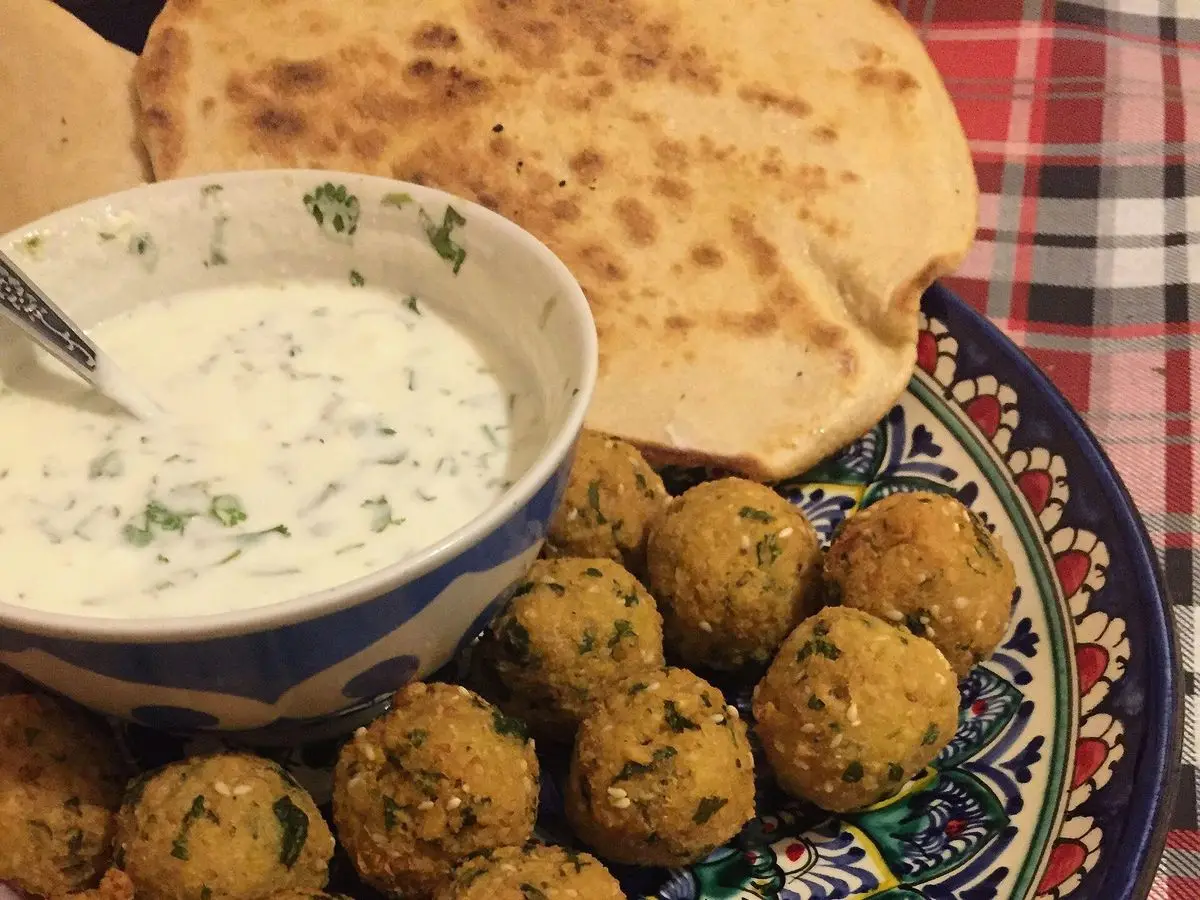 Plato decorado con croquetas de falafel verdes y un cuenco de salsa de yogur