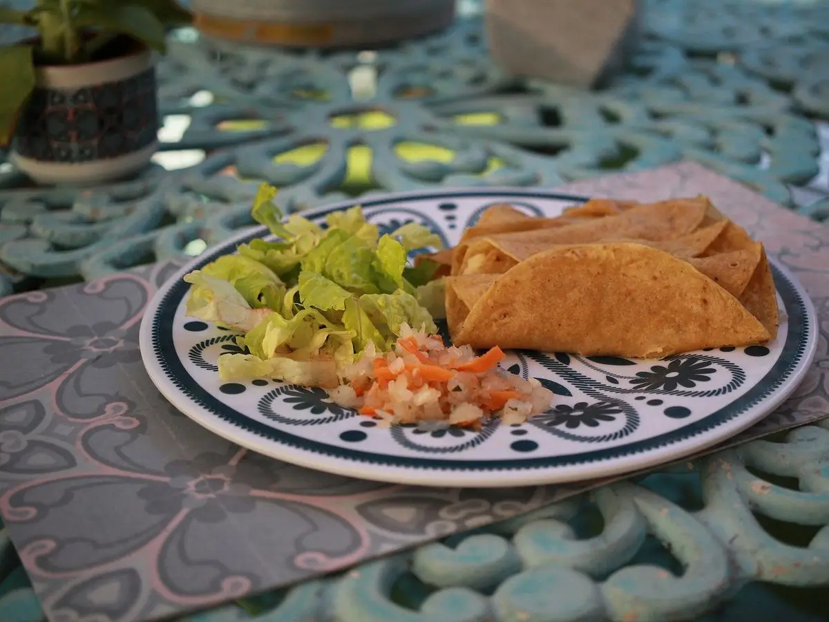 Plato estampado con tacos dorados de papa, lechuga y salsa de tomate