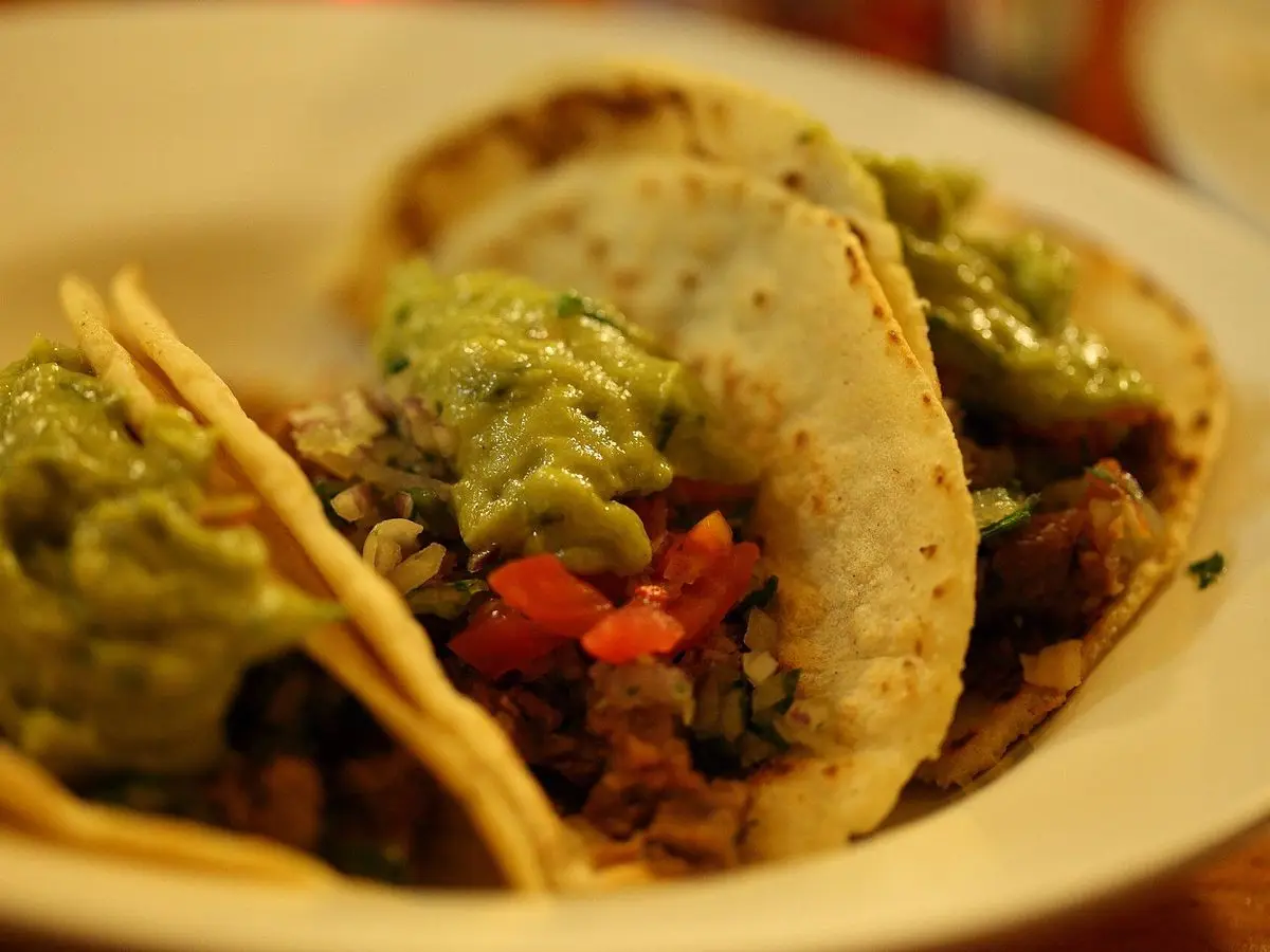 Tacos de carne con guacamole y tomate picado en un plato