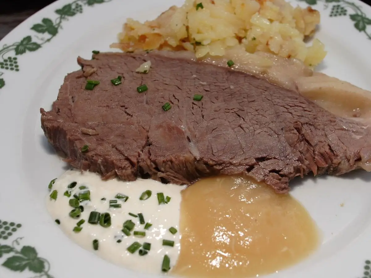 Ternera hervida en lonchas con salsa de cebollino, compota de manzana y patatas en un plato