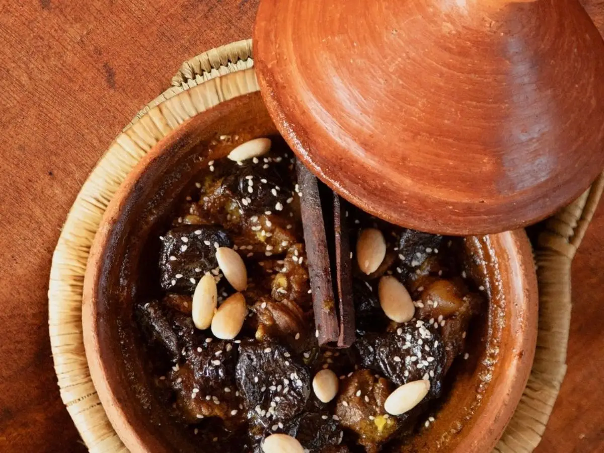 Tajín de barro con cordero, ciruelas pasas y almendras laminadas, con canela en rama