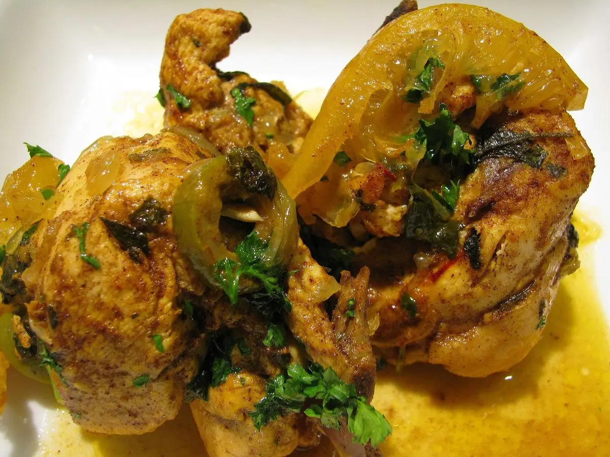 Tajín de pollo con limón en conserva, aceitunas y hierbas frescas sobre salsa amarilla