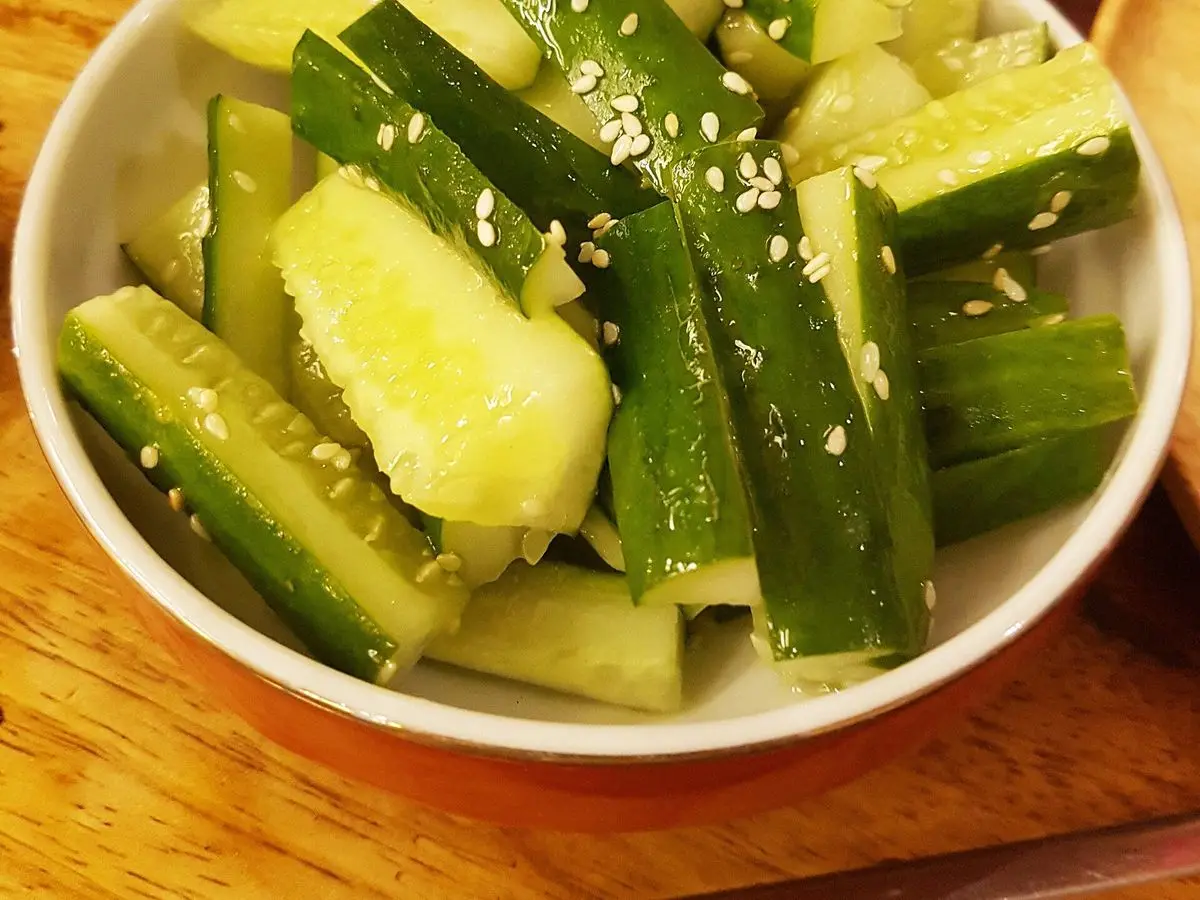Cuenco blanco de pepino troceado y machacado con sésamo, ensalada fresca tailandesa